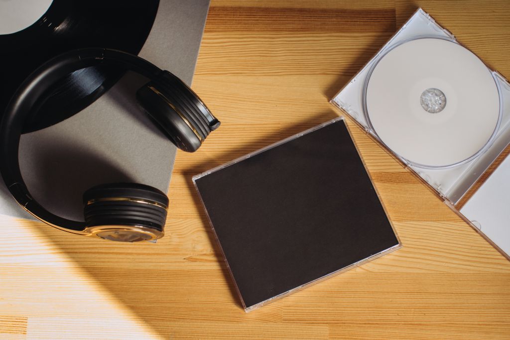 CD and case on wooden table next to headphones